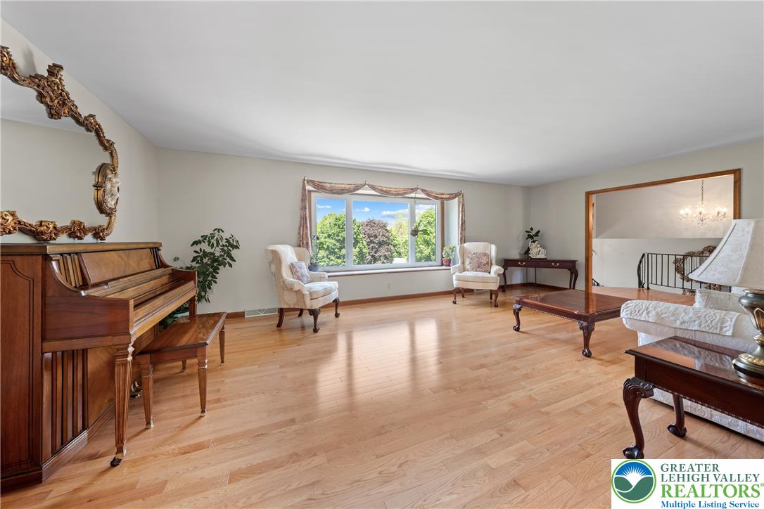 947 Tamenend Road Bath, PA 18014 - Photo 17 of 61 Hardwood floors stretch across this elegant living room, illuminated by a large picture window framing lush outdoor views.