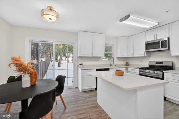 a open kitchen with stainless steel appliances granite countertop a stove top oven a refrigerator a sink dishwasher a dining table and chairs with wooden floor