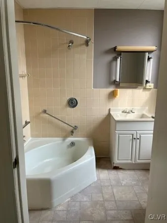 a bathroom with a tub a sink a mirror and a shower