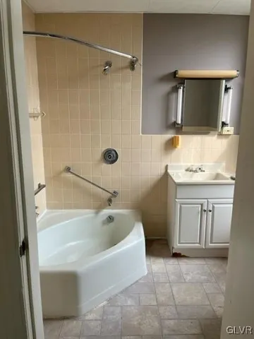 a bathroom with a tub a sink a mirror and a shower
