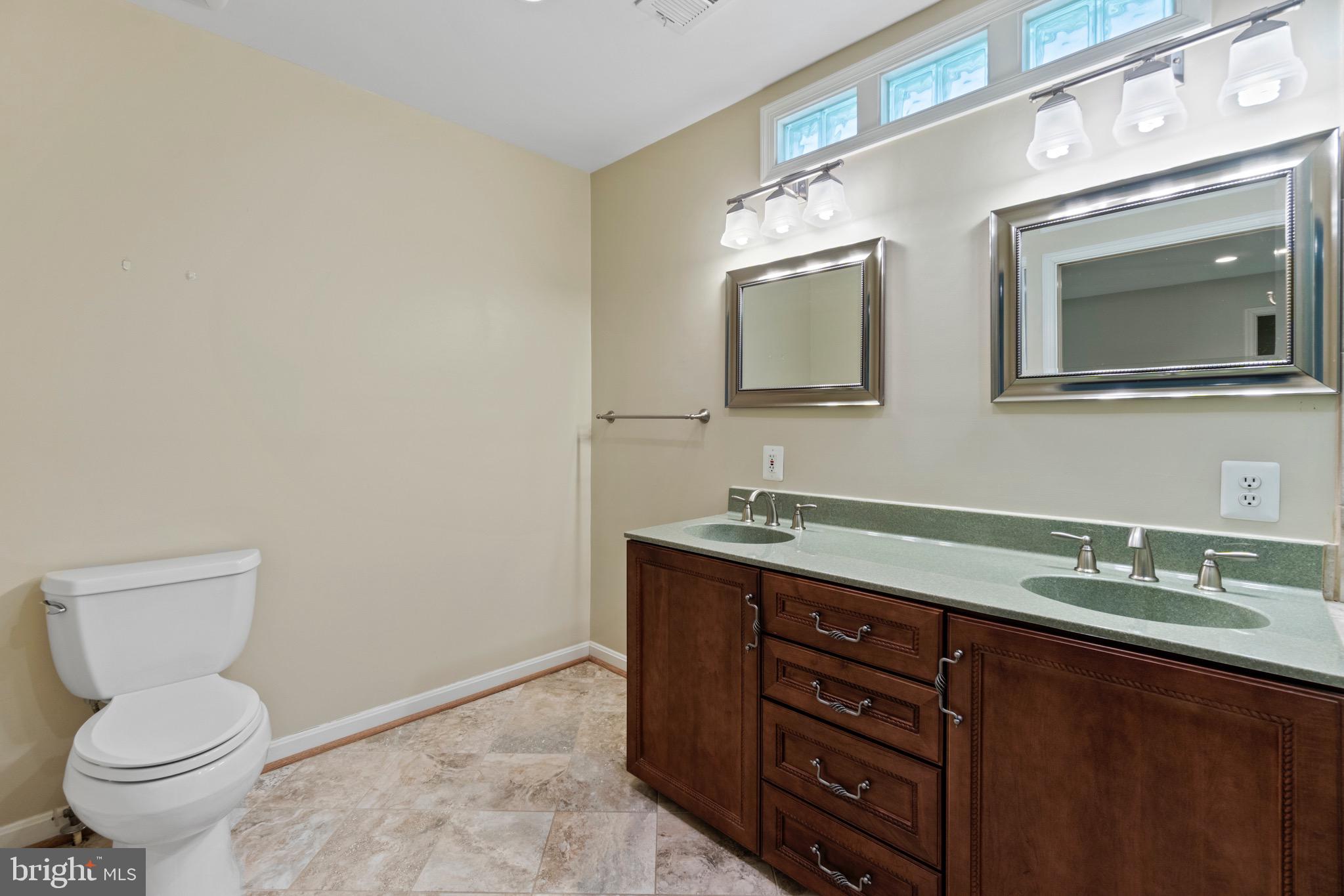 7409 Warfield Road Gaithersburg, MD 20882 - Photo 13 of 22 a bathroom with a granite countertop toilet sink and mirror
