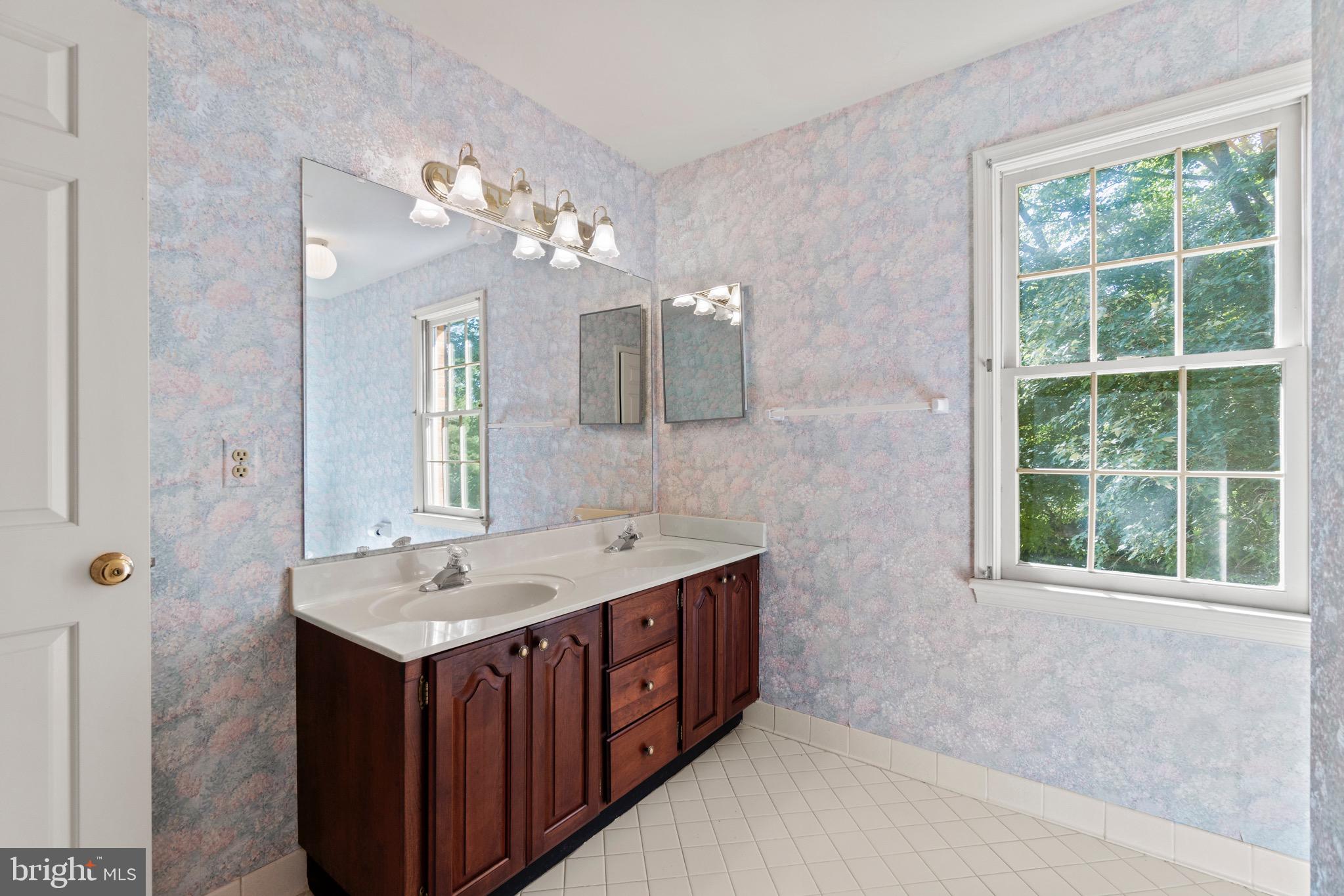 7409 Warfield Road Gaithersburg, MD 20882 - Photo 14 of 22 a bathroom with a double vanity sink a large mirror and a bathtub