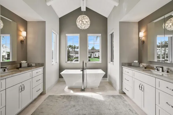 a spacious bathroom with a double vanity sink a large mirror a bathtub and window