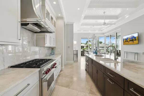 a kitchen with kitchen island stainless steel appliances a stove a sink a refrigerator and chairs