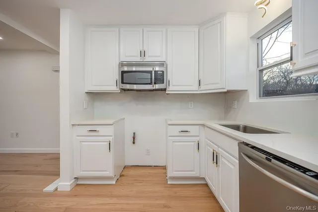 a kitchen with stainless steel appliances white cabinets and a stove top oven