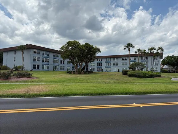 a view of a big house with a big yard and large trees