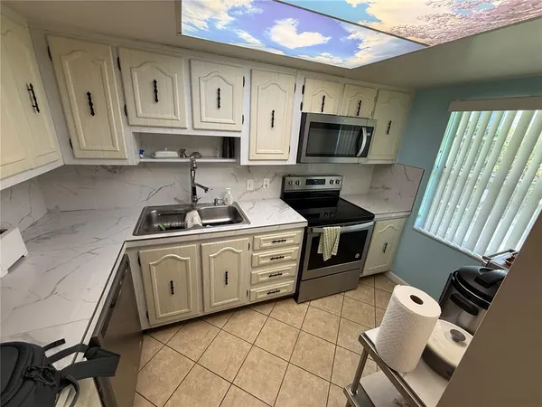 a kitchen with stainless steel appliances a stove a sink and white cabinets