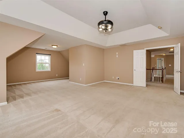 a view of an empty room with window and kitchen view