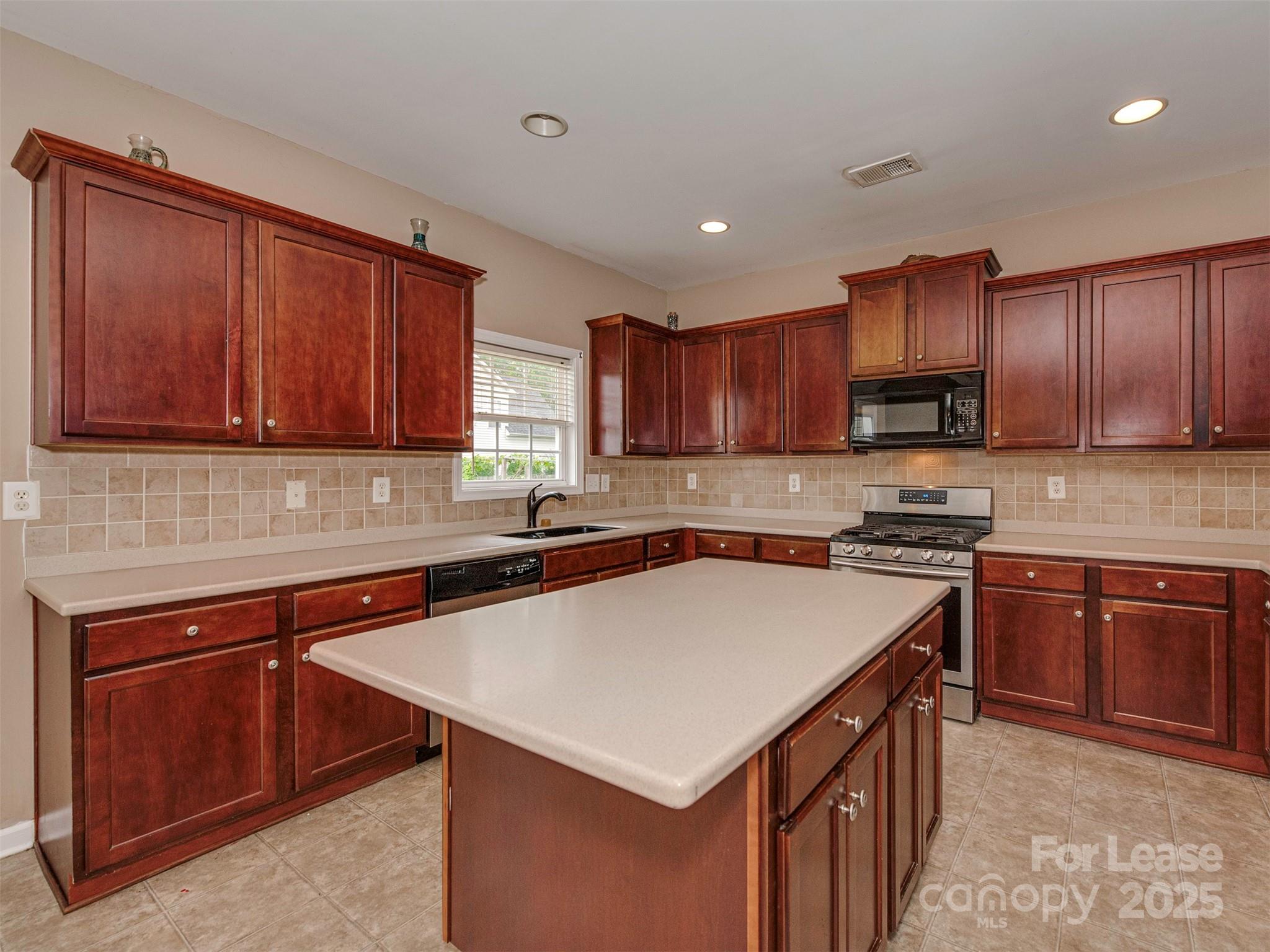 5607 Fulton Ridge Drive Indian Trail, NC 28079 - Photo 6 of 27 a kitchen with stainless steel appliances a sink a stove a refrigerator cabinets and a kitchen island