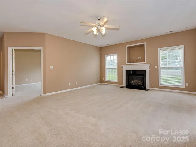 a view of an empty room with window and fireplace