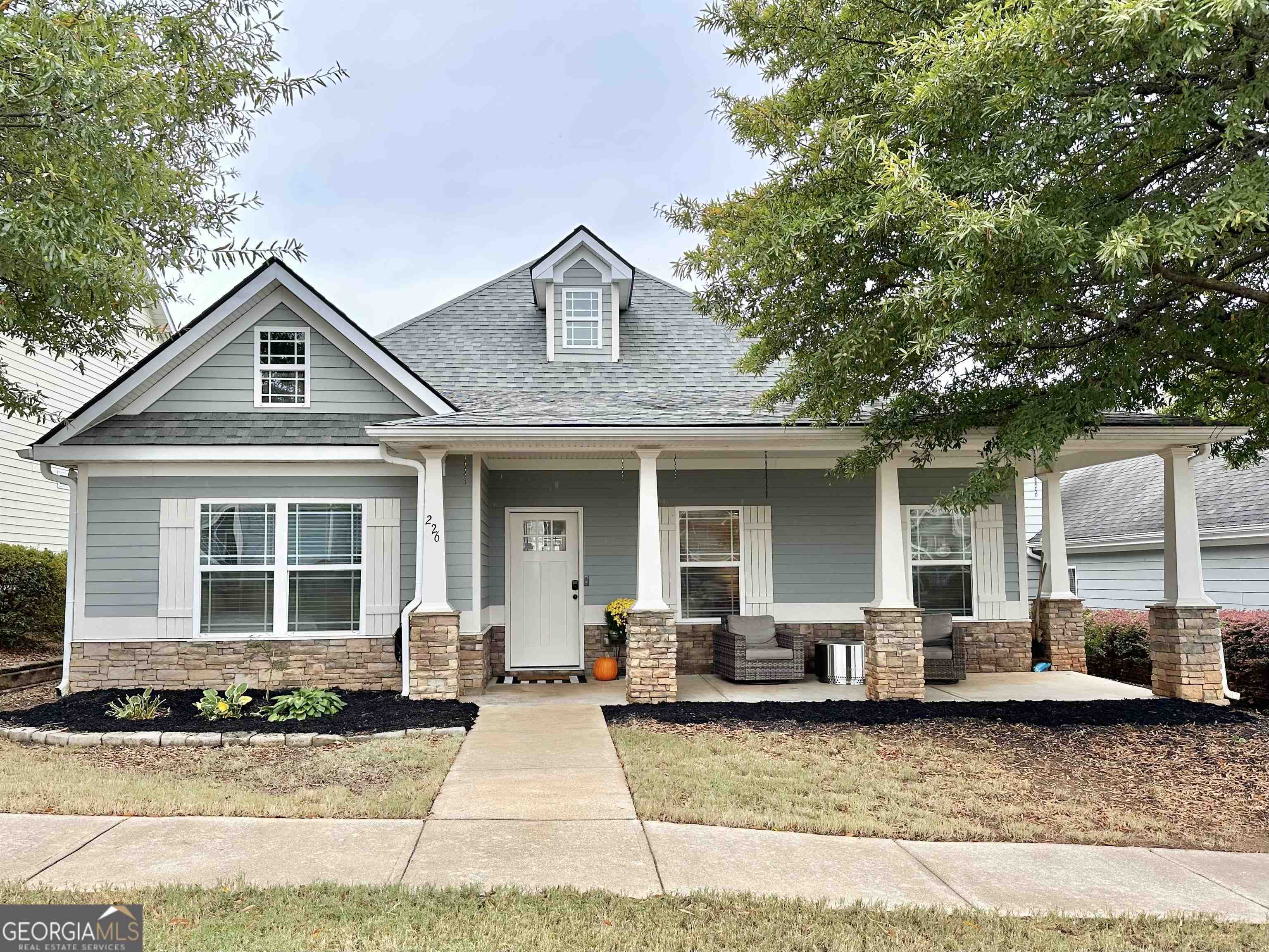 a front view of a house with lots of furniture and plants