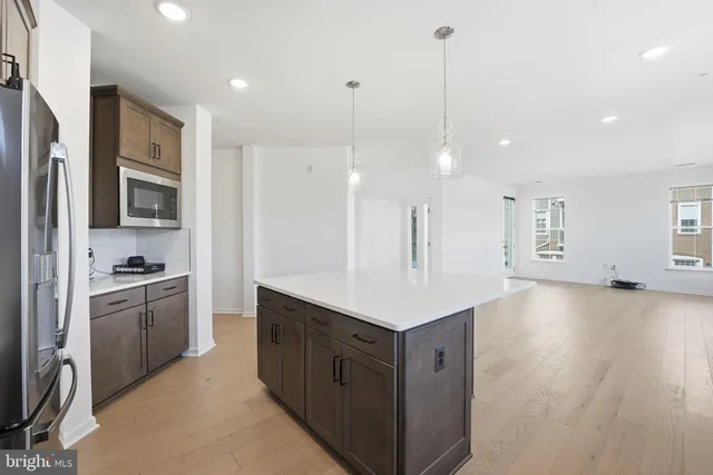 a kitchen with stainless steel appliances granite countertop a sink a stove a refrigerator cabinets and wooden floor