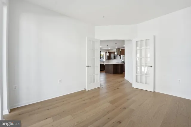 a view of a kitchen and an empty room with wooden floor and windows