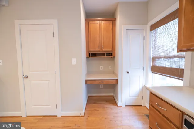 a view of an empty room with wooden floor and fan