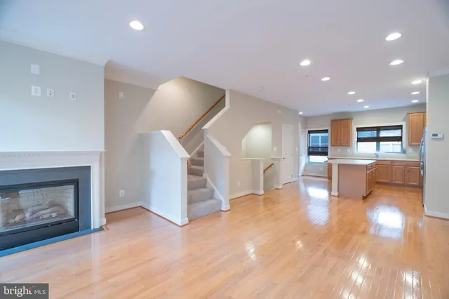 a view of an empty room with wooden floor fireplace and a window