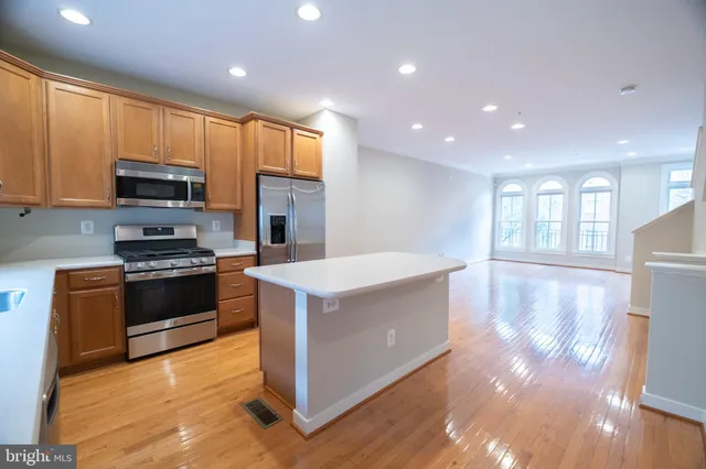 a kitchen with stainless steel appliances kitchen island granite countertop a stove a sink and a refrigerator