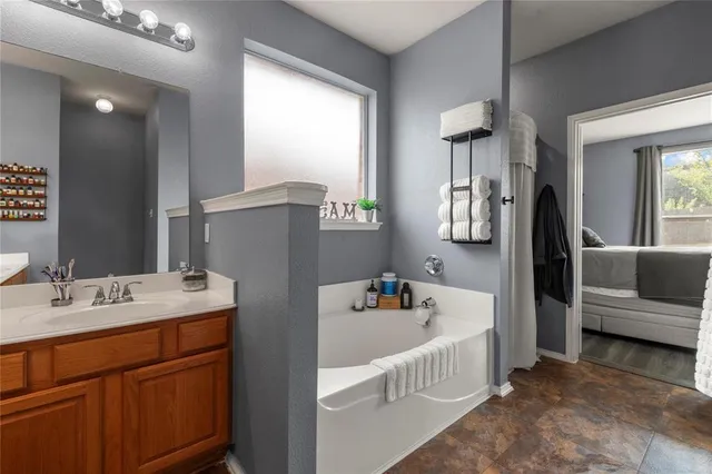 a bathroom with a tub a sink and mirror