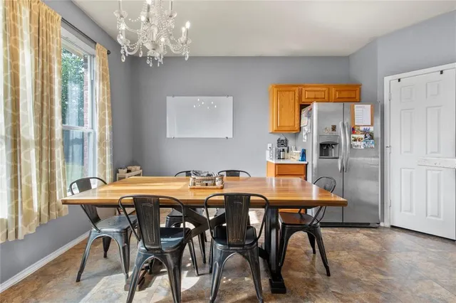 a room with stainless steel appliances dining table chairs and a refrigerator