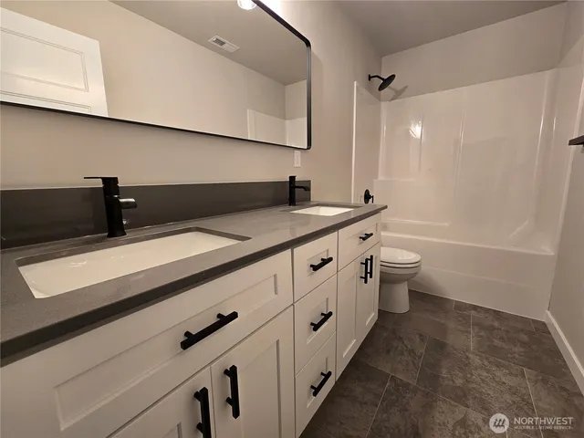 a bathroom with a granite countertop sink a toilet and vanity