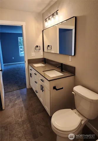 a bathroom with a granite countertop toilet sink and mirror