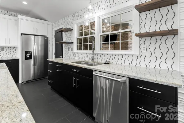 a kitchen with stainless steel appliances granite countertop a refrigerator a sink and wooden cabinets