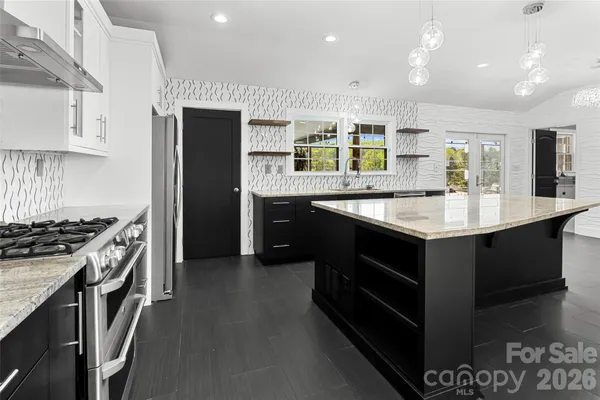 a large kitchen with stainless steel appliances granite countertop a stove and a sink