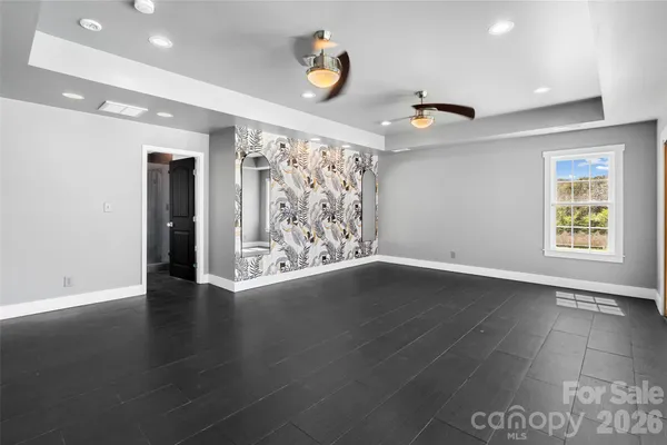 an empty room with wooden floor chandelier fan and windows