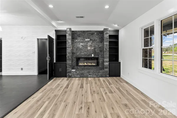 an empty room with wooden floor fireplace and windows