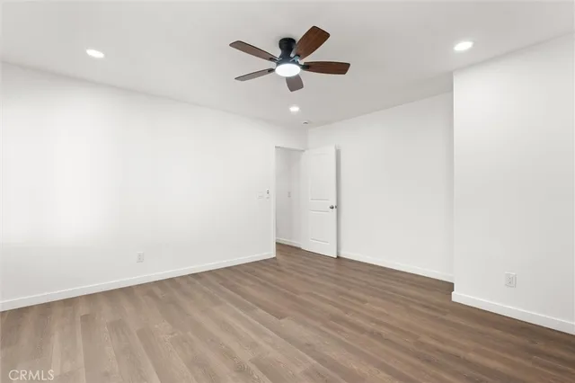 an empty room with wooden floor and ceiling fan