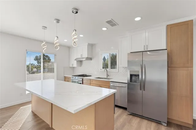 a kitchen with kitchen island a counter top space stainless steel appliances and cabinets