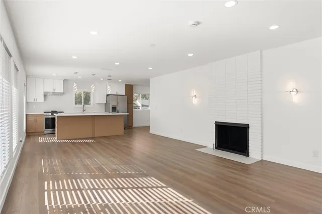 a large white kitchen with kitchen island a sink dishwasher a stove and a refrigerator with wooden floor