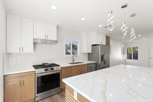 a kitchen with stainless steel appliances a refrigerator sink and stove