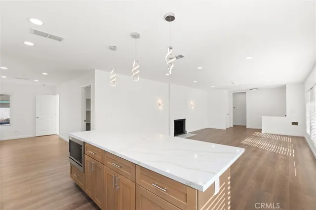 a large white kitchen with a sink a refrigerator and wooden floor