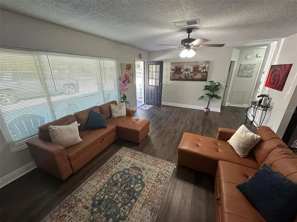 a kitchen with stainless steel appliances granite countertop a dining table chairs refrigerator and microwave