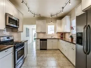 a kitchen with stainless steel appliances granite countertop a refrigerator a sink a stove top oven a sink and dishwasher