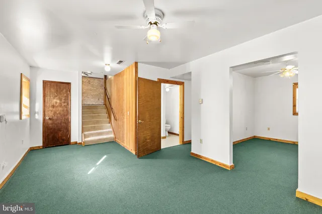 an empty room with a fan & a window