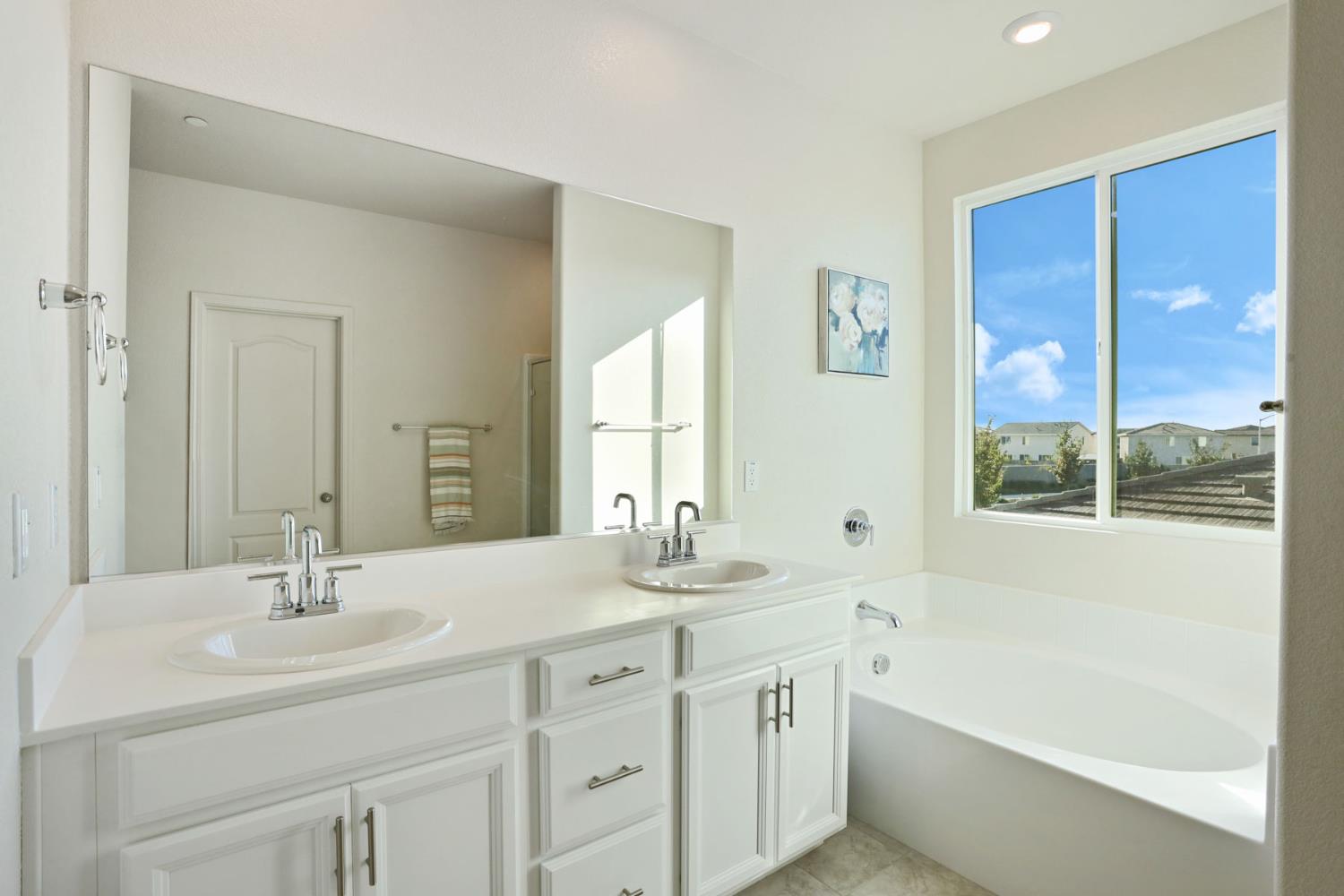 2004 Ravine Lane Manteca, CA 95337 - Photo 18 of 28 a bathroom with a double vanity sink a large mirror a bathtub and next to a window