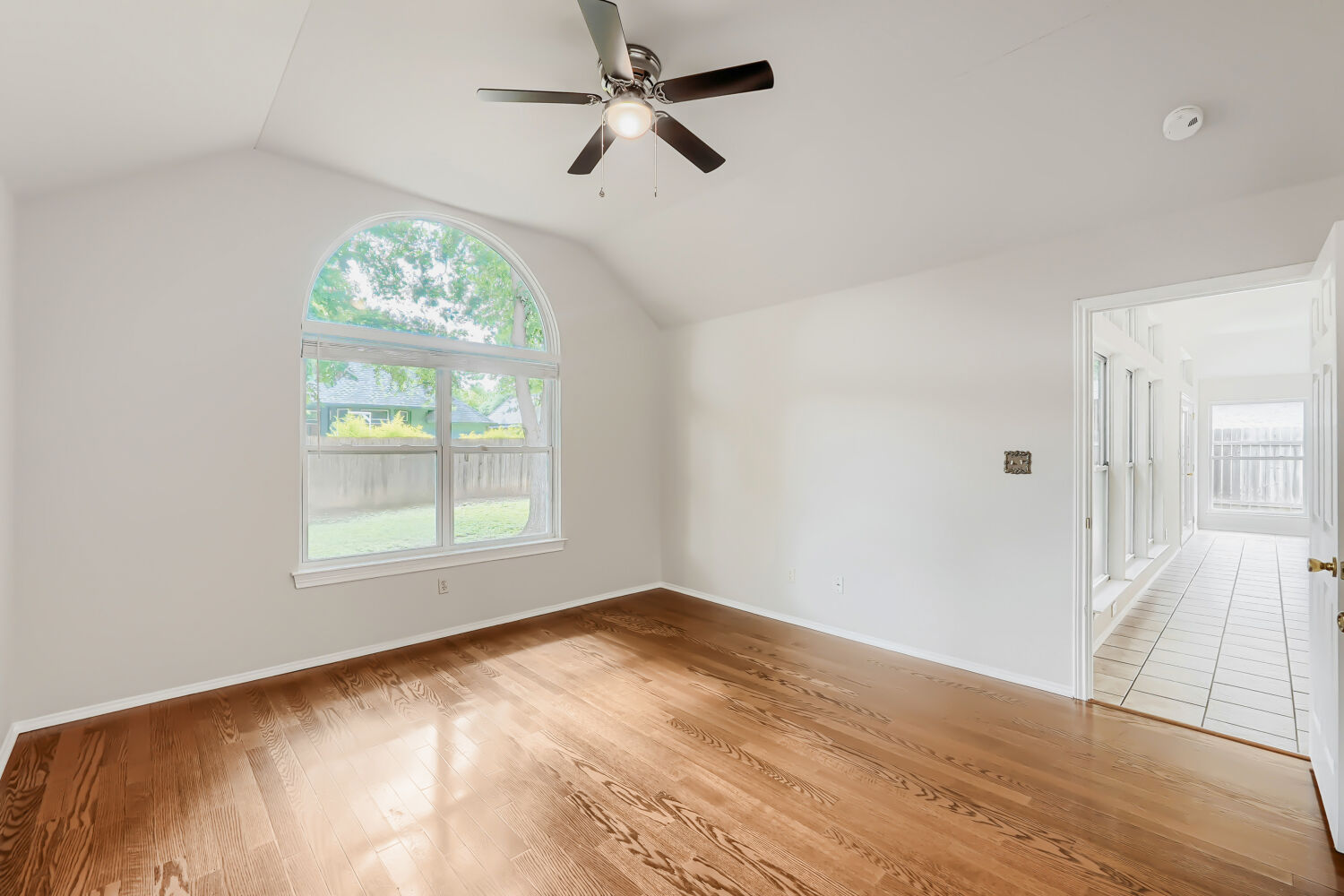 119 Stephen Lane Georgetown, TX 78626 - Photo 13 of 32 A spacious primary bedroom features vaulted ceilings, rich hardwood flooring, and a graceful arched window.