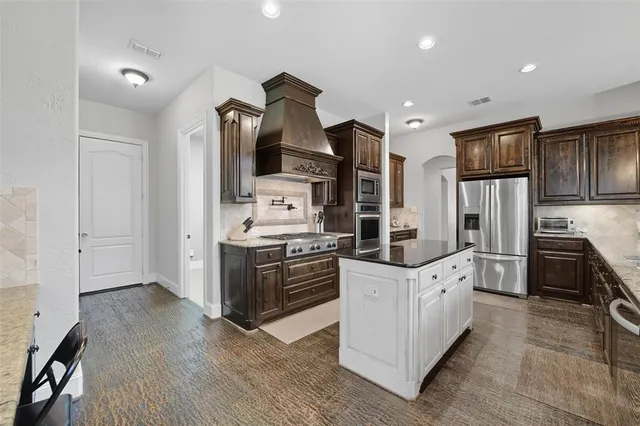 a kitchen with stainless steel appliances granite countertop a stove top oven and refrigerator