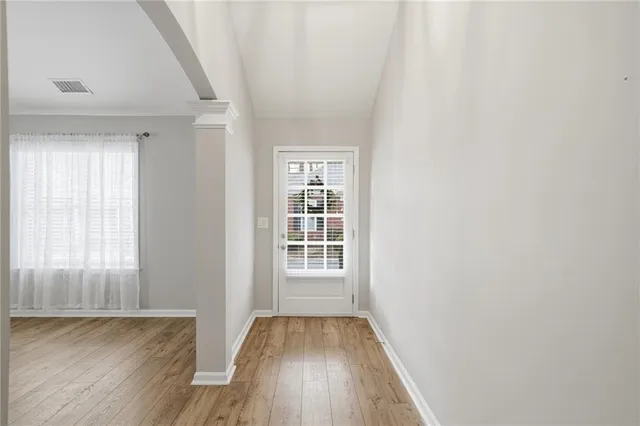a view of an empty room with wooden floor and a window