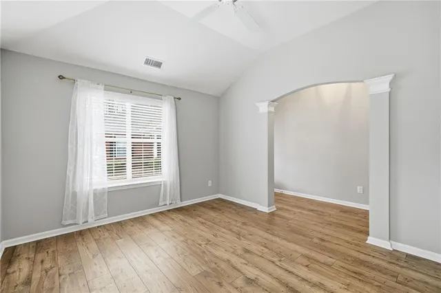 an empty room with wooden floor and windows
