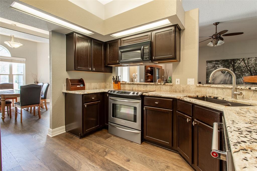 8950 Southeast 17th Court Ocala, FL 34480 - Photo 17 of 61 a kitchen with stainless steel appliances granite countertop a stove top oven a sink dishwasher a dining table and chairs with wooden floor