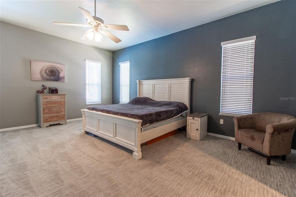 8950 Southeast 17th Court Ocala, FL 34480 - Photo 20 of 61 a spacious bedroom with a bed a chandelier and a couch