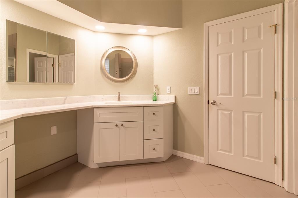 8950 Southeast 17th Court Ocala, FL 34480 - Photo 27 of 61 a bathroom with a granite countertop sink a mirror and a vanity