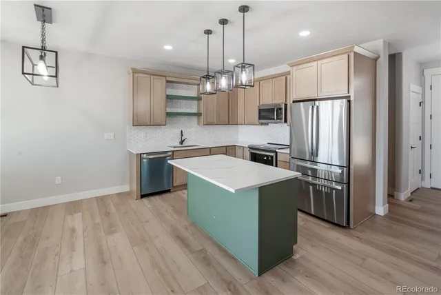 a kitchen with stainless steel appliances granite countertop a sink a stove a refrigerator and a microwave