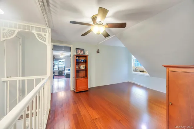 a view of a room with wooden floor staircase and a ceiling fan