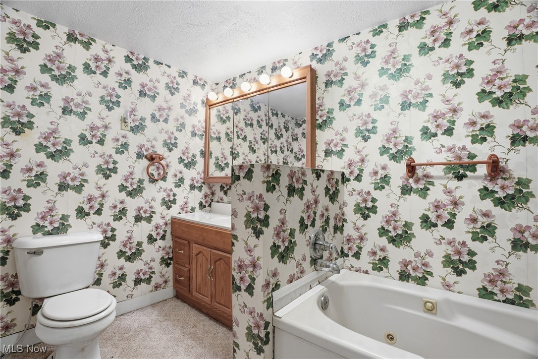 8045 Veto Road Belpre, OH 45714 - Photo 40 of 50 Bathroom with wallpapered walls, a textured ceiling, a whirlpool tub, and vanity