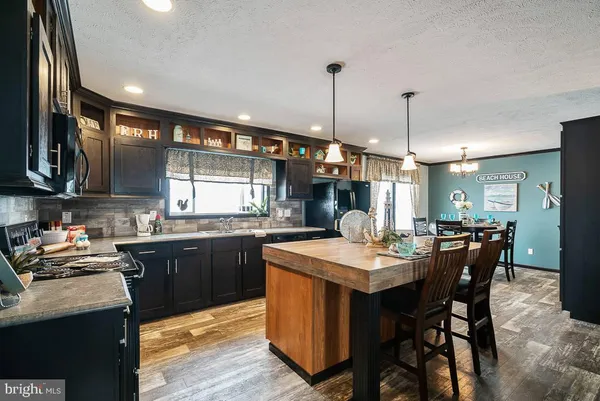 a kitchen with stainless steel appliances kitchen island granite countertop a sink a stove and a wooden floors
