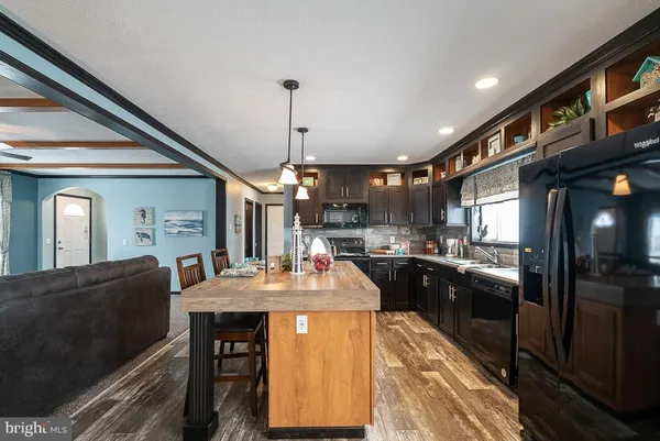 a kitchen with stainless steel appliances kitchen island granite countertop a stove top oven a sink dishwasher and cabinets with wooden floor
