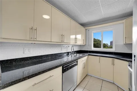 a white kitchen with granite countertop white cabinets and a sink